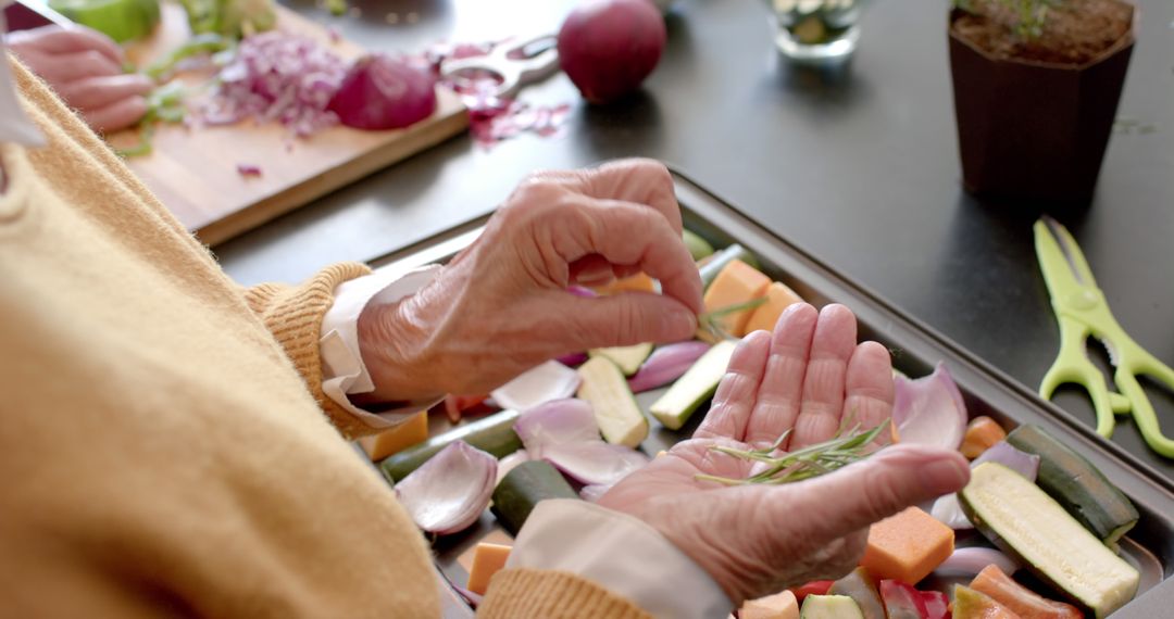 Elderly Woman Seasoning Vegetables on Baking Sheet for Cooking - Free Images, Stock Photos and Pictures on Pikwizard.com