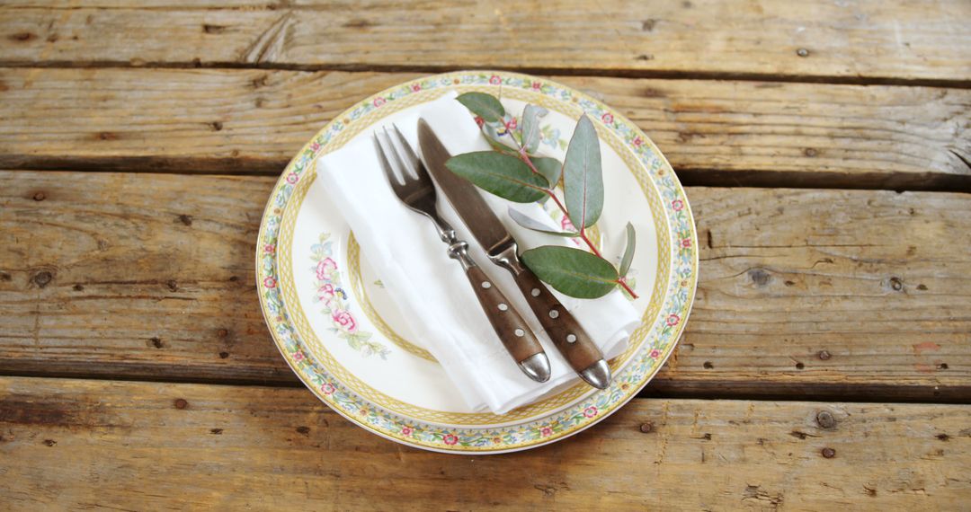 A vintage plate and cutlery set on a wooden table create a charming dining ambiance. - Free Images, Stock Photos and Pictures on Pikwizard.com