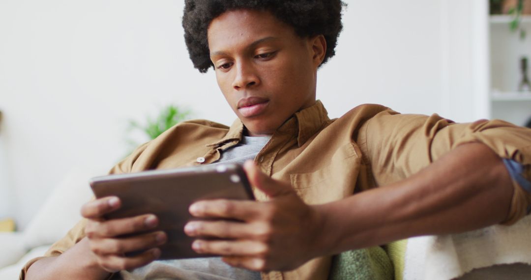 Young Man Relaxing at Home Using Tablet Device