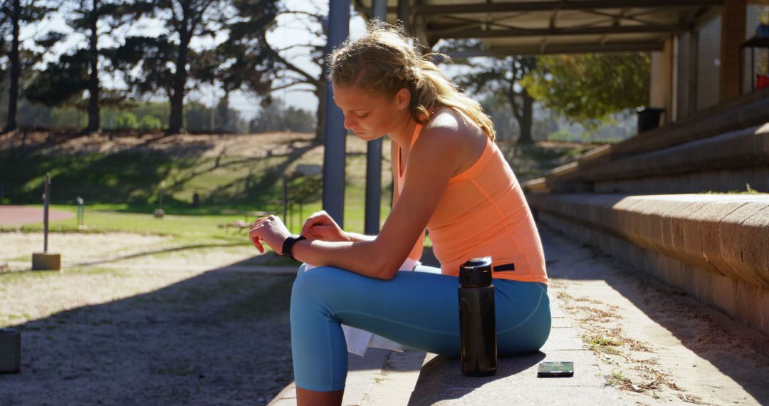 Athletic Woman Resting and Checking Smartwatch at Training Ground - Free Images, Stock Photos and Pictures on Pikwizard.com