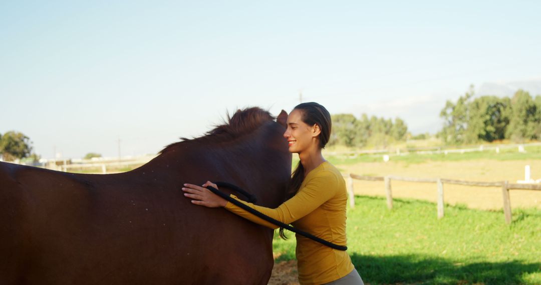 A young Asian woman gently embraces a horse in a sunny outdoor setting, with copy space - Free Images, Stock Photos and Pictures on Pikwizard.com