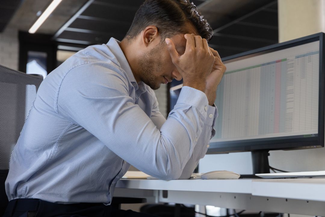 Stressed Businessman Analyzing Spreadsheets in Office