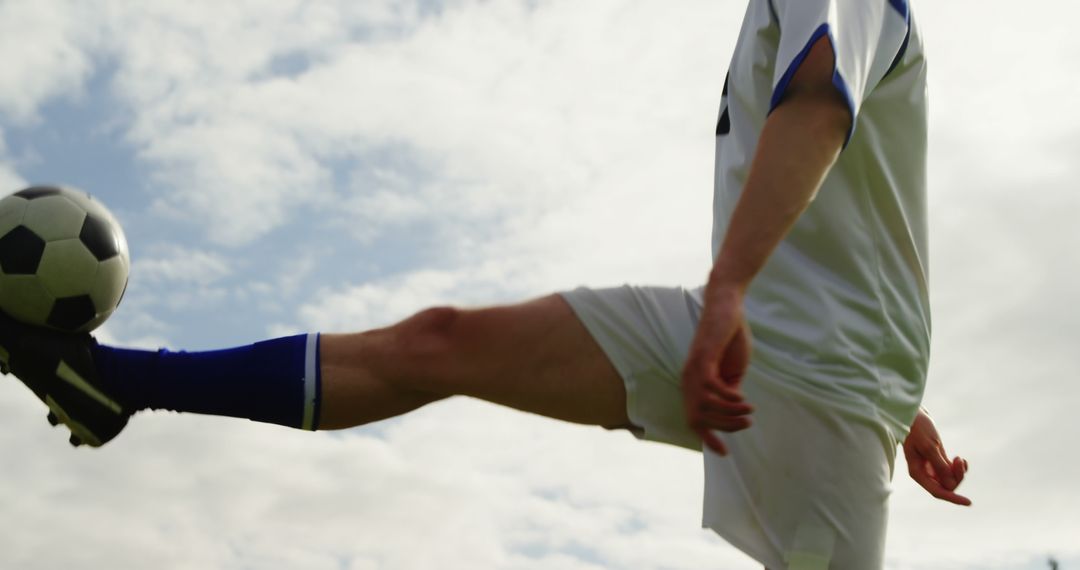 A soccer player in a white and blue uniform is about to kick a soccer ball, with copy space - Free Images, Stock Photos and Pictures on Pikwizard.com