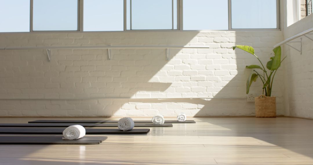 Bright Sunlit Yoga Studio with Rolled Mats and Towels