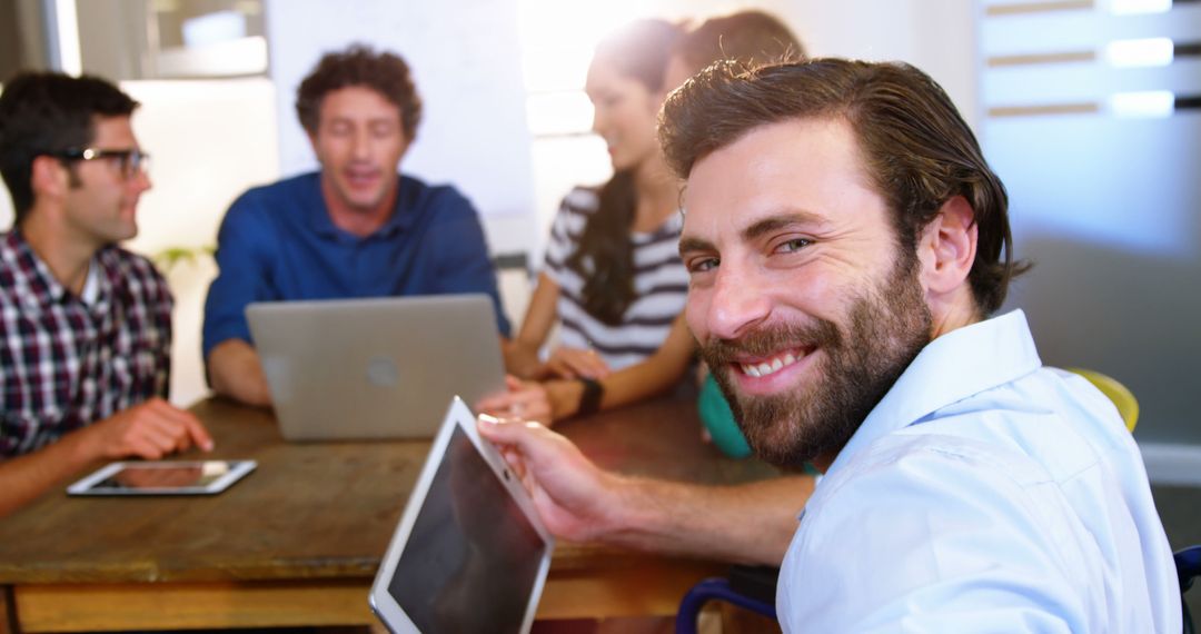 Smiling Businessman Holding a Digital Tablet during Team Meeting - Free Images, Stock Photos and Pictures on Pikwizard.com