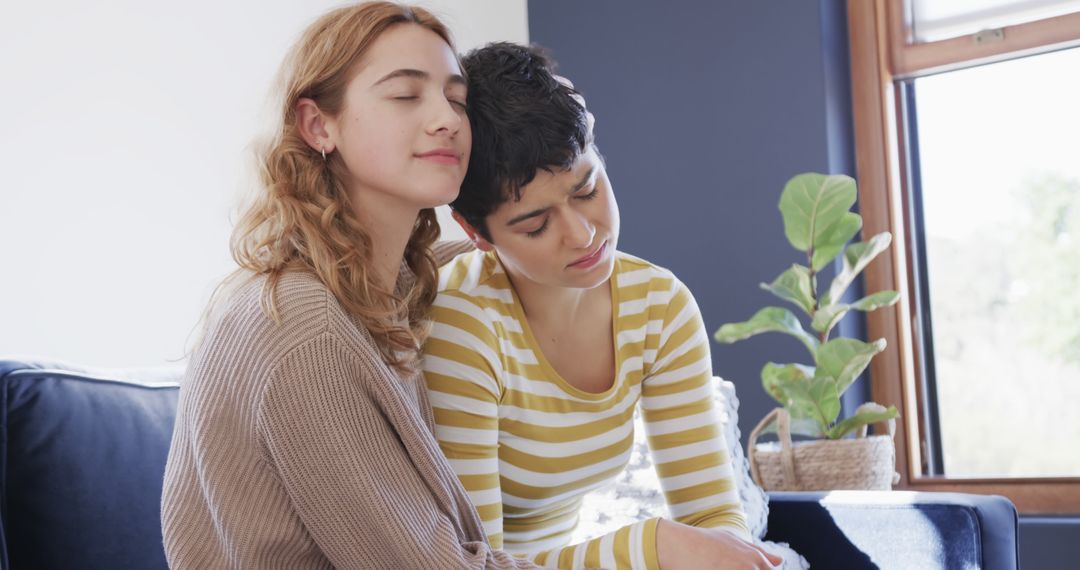 Lesbian Couple Happily Embracing on Sofa in Sunlit Living Room