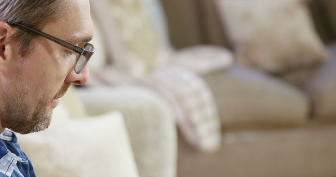 Man with Glasses Deep in Thought on Sofa - Free Images, Stock Photos and Pictures on Pikwizard.com