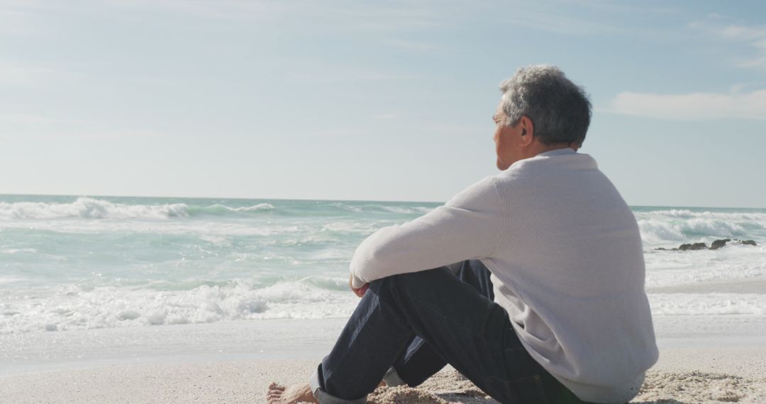 Senior Man Relaxing by Ocean Waves on Beach