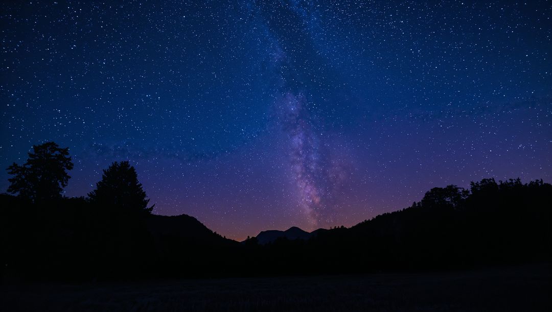 Milky Way Rising Over Silhouetted Ridge and Trees Under Starry Twilight Sky