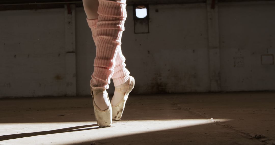 Ballet Dancer on Pointe Wearing Pink Leg Warmers in Sunbeam - Free Images, Stock Photos and Pictures on Pikwizard.com