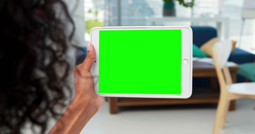 Person Holding Tablet with Green Screen in Modern Living Room - Free Images, Stock Photos and Pictures on Pikwizard.com