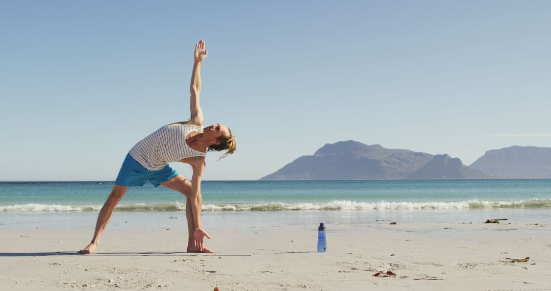 Man Practicing Yoga on Beach by Ocean and Mountains - Free Images, Stock Photos and Pictures on Pikwizard.com