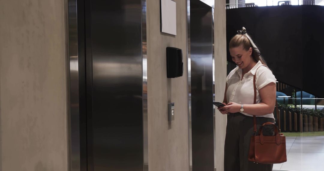 Professional at Elevator Door Checking Smartphone in Modern Office Lobby