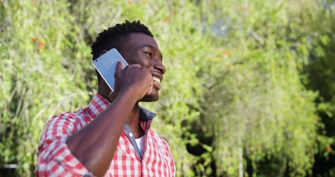 Young Man Smiling While Talking on Smartphone Outdoors - Free Images, Stock Photos and Pictures on Pikwizard.com