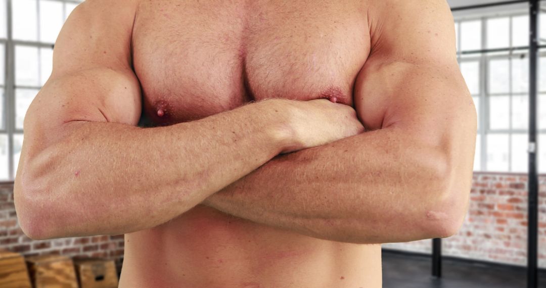 Muscular Man Crossing Arms Confidently in Modern Gym Setting