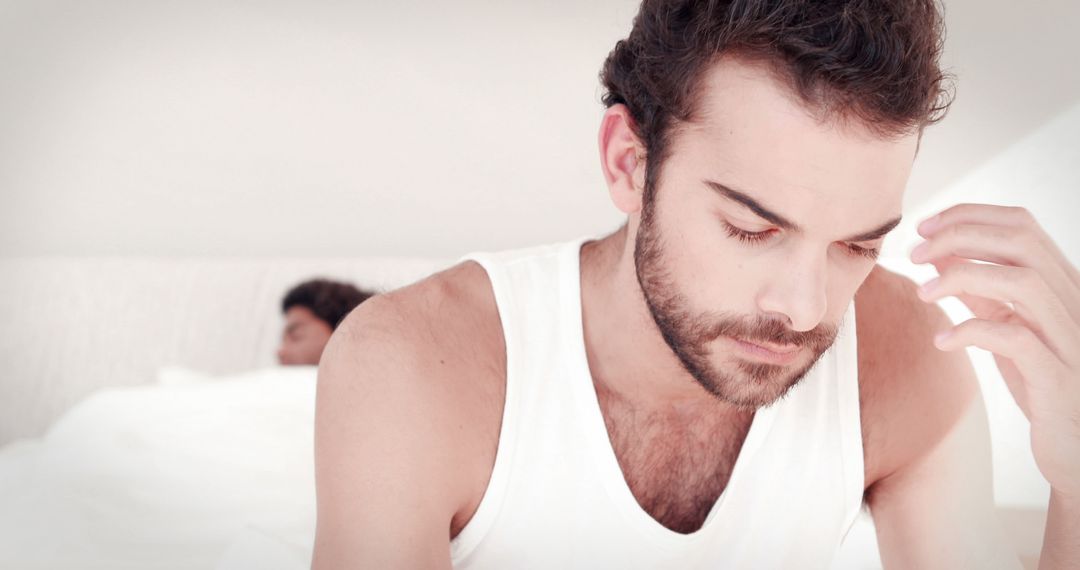 Worried Man Sitting on Bed in White Tank Top - Free Images, Stock Photos and Pictures on Pikwizard.com