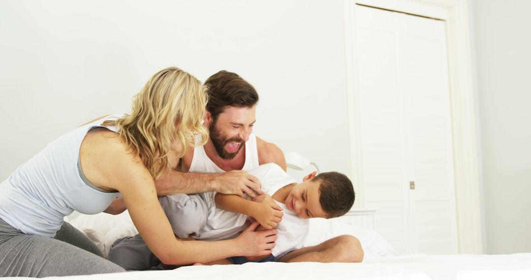 Playful Family Tickle Fight On Bed Brings Laughter and Bonding - Free Images, Stock Photos and Pictures on Pikwizard.com