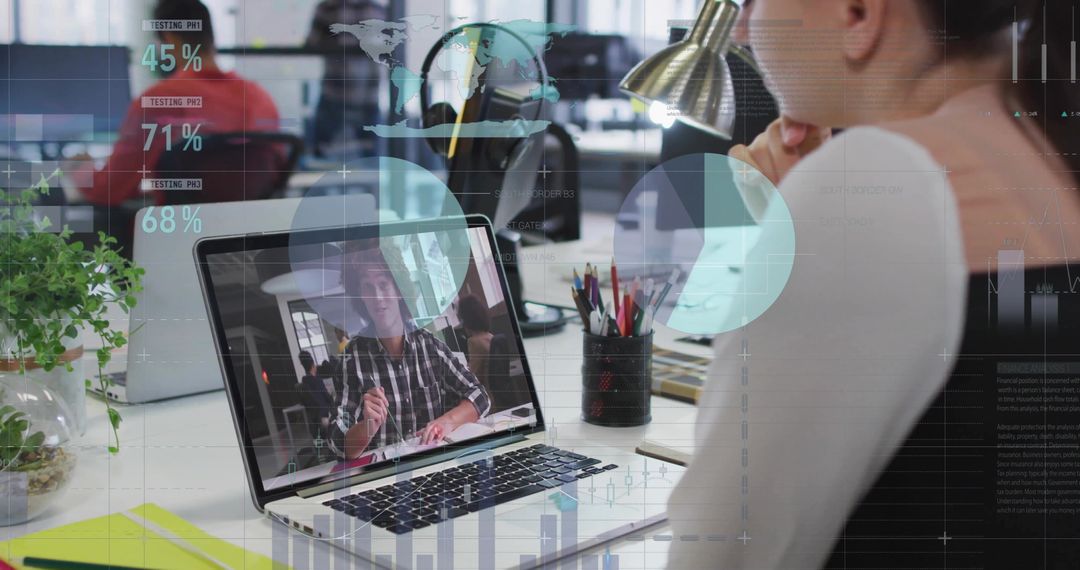 Woman watching remote video call on laptop in modern open office with analytics HUD