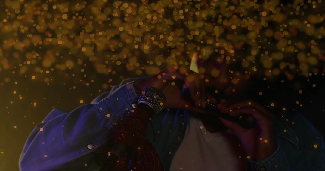 Musician in Denim Jacket Blowing Harmonica on Dimly Lit Stage with Golden Bokeh