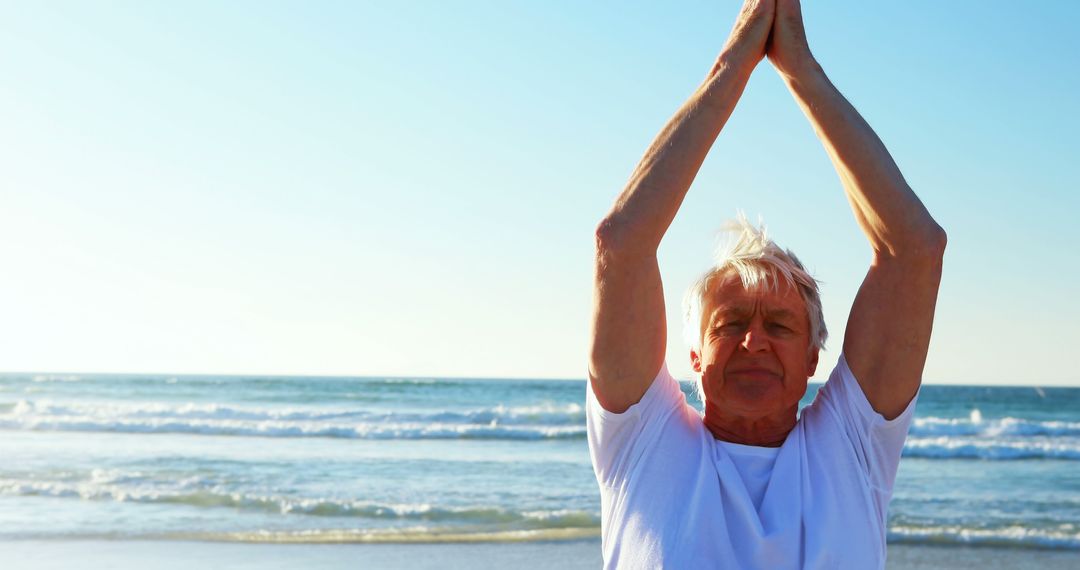 Senior man practicing yoga on beach under clear blue sky - Free Images, Stock Photos and Pictures on Pikwizard.com