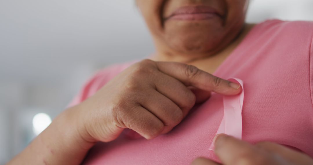 Close-Up of Woman Pinning Pink Ribbon on Shirt for Breast Cancer Awareness - Free Images, Stock Photos and Pictures on Pikwizard.com