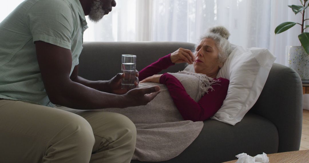 Worried Man Giving Sick Woman Glass of Water on Couch - Free Images, Stock Photos and Pictures on Pikwizard.com