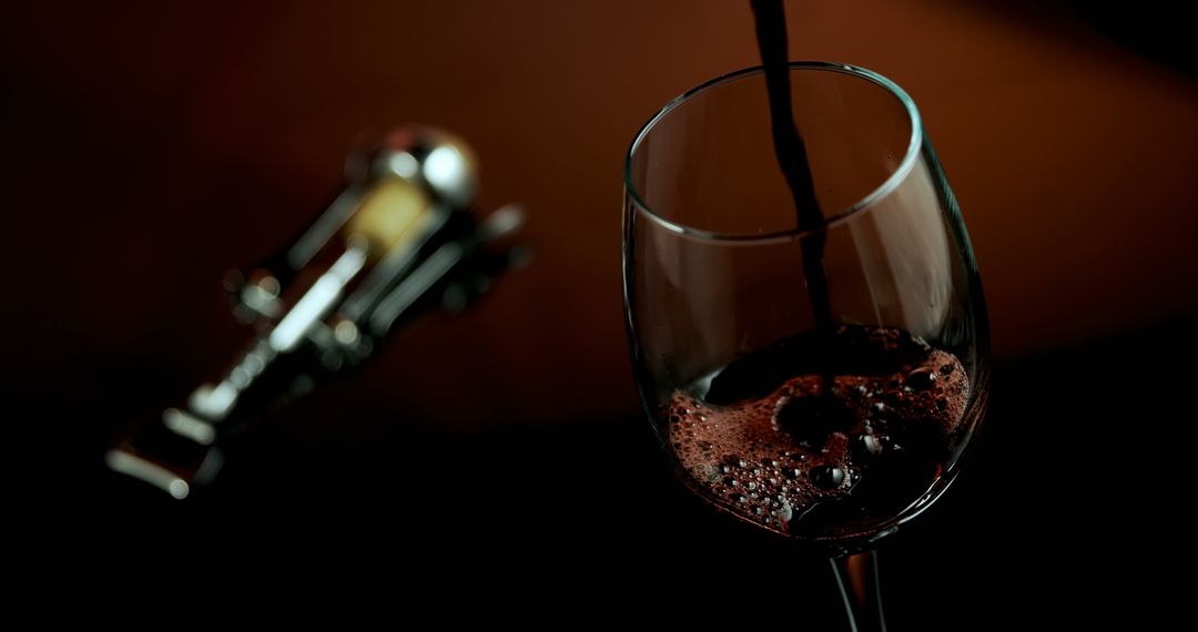 Red Wine Pouring into Glass with Corkscrew in Elegant Setting