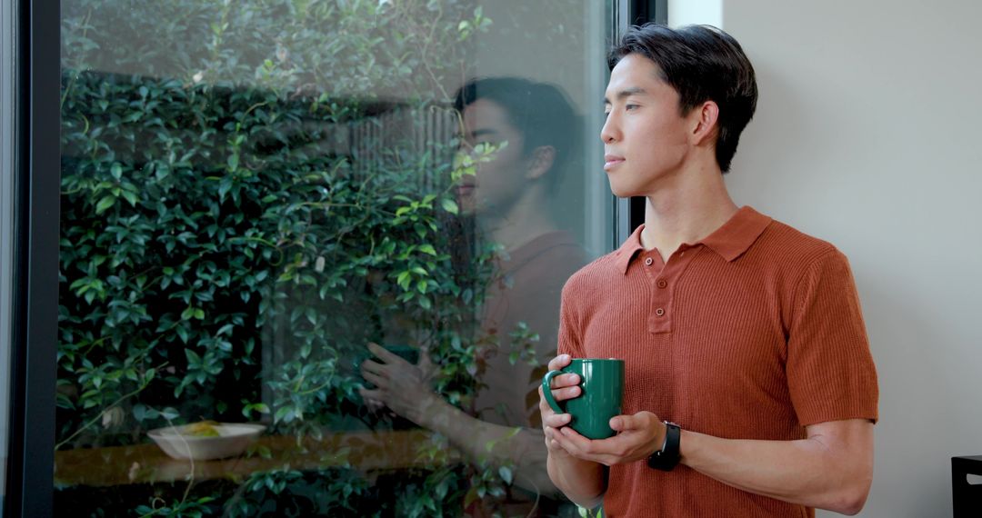 Serene Reflection: Asian Man Enjoying Coffee by Window