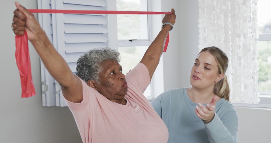 Elderly Woman Exercising with Resistance Band Assisted by Caregiver - Free Images, Stock Photos and Pictures on Pikwizard.com