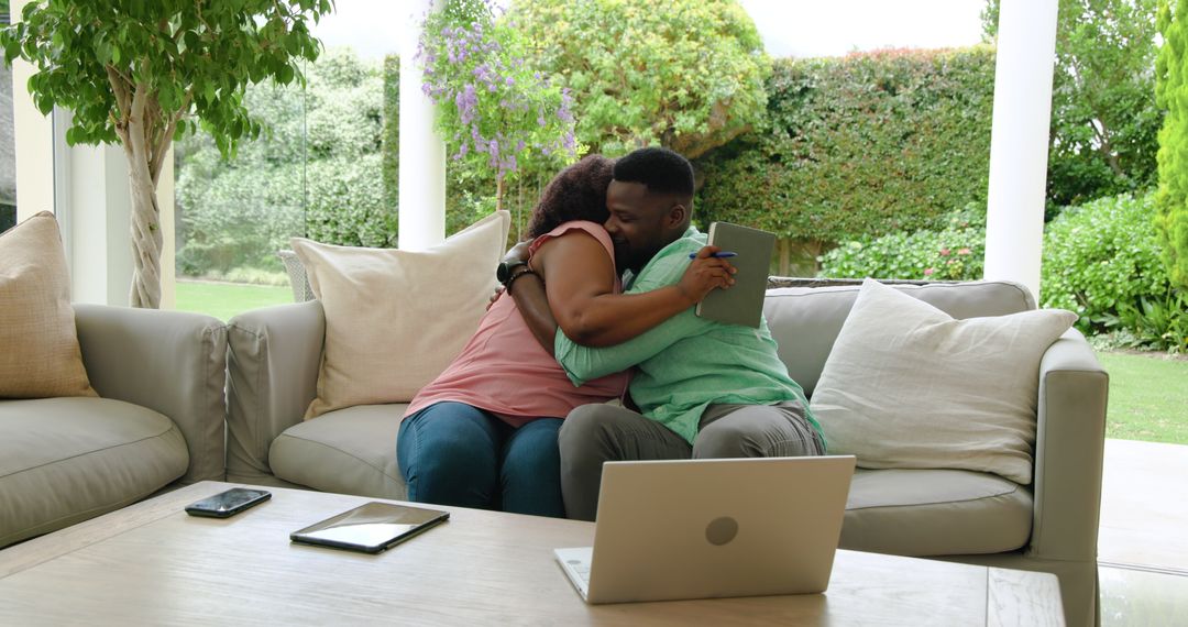 Couple Embracing on Sofa Sharing Technology at Home