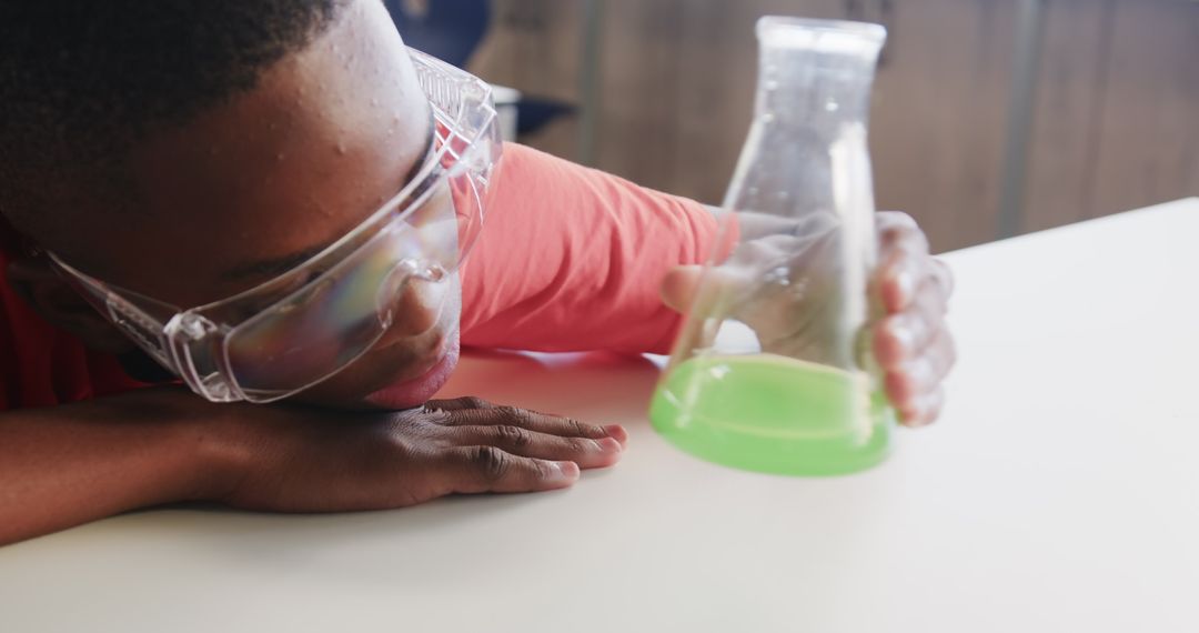 Curious boy examining green liquid in science lab