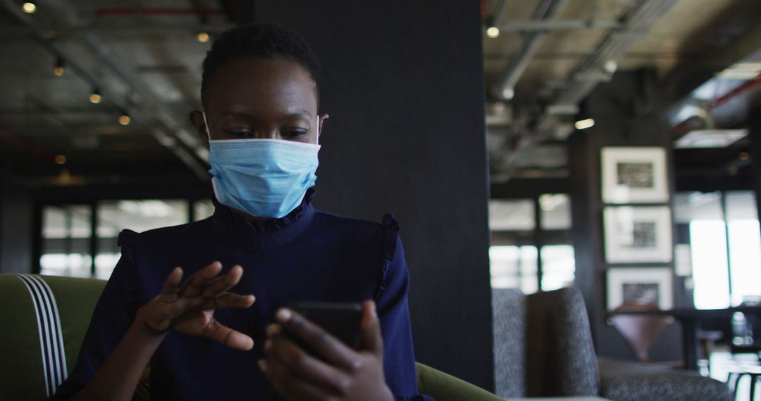 Woman Wearing Face Mask Using Smartphone in Modern Office Space - Free Images, Stock Photos and Pictures on Pikwizard.com