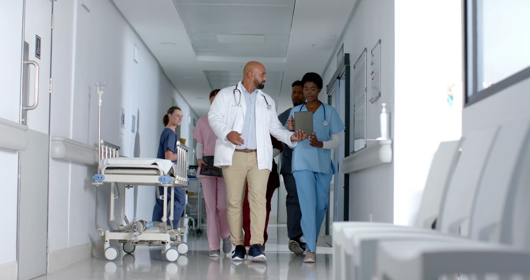 Medical Team Walking Through Hospital Corridor Discussing Patient Care - Free Images, Stock Photos and Pictures on Pikwizard.com