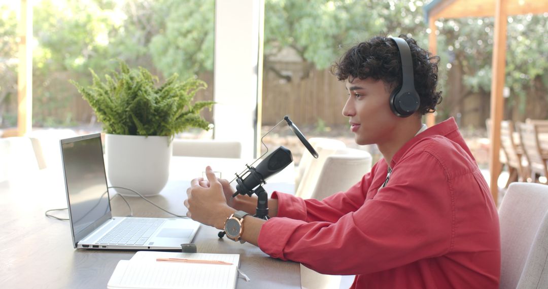 Young Man Recording Podcast with Laptop and Microphone at Home