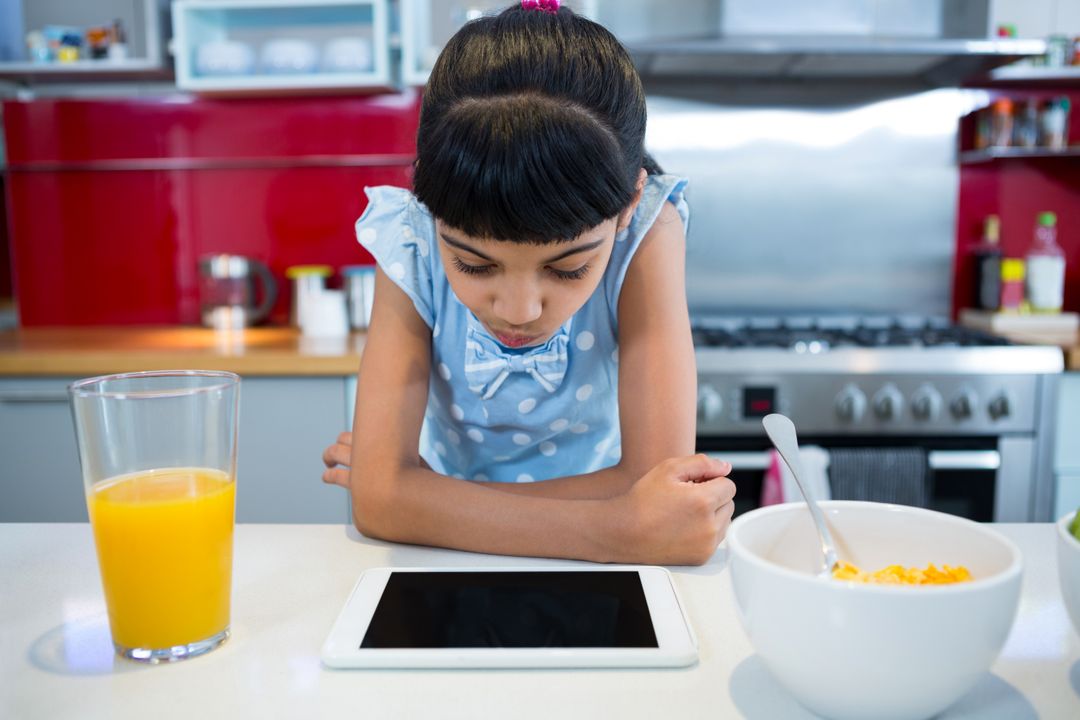 Girl Using Tablet During Breakfast in Modern Kitchen - Free Images, Stock Photos and Pictures on Pikwizard.com