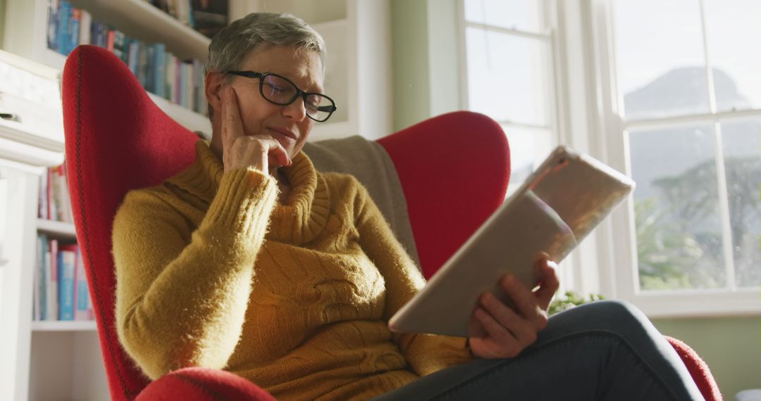 Senior Woman Reading Tablet in Sunny Cozy Living Room - Free Images, Stock Photos and Pictures on Pikwizard.com