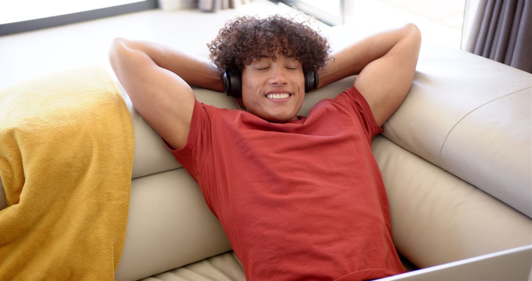 Young Man Relaxing on Sofa with Headphones at Home