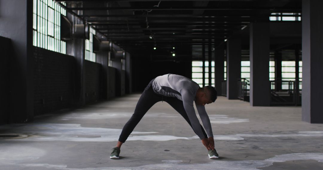 Man Stretching in Abandoned Warehouse - Free Images, Stock Photos and Pictures on Pikwizard.com