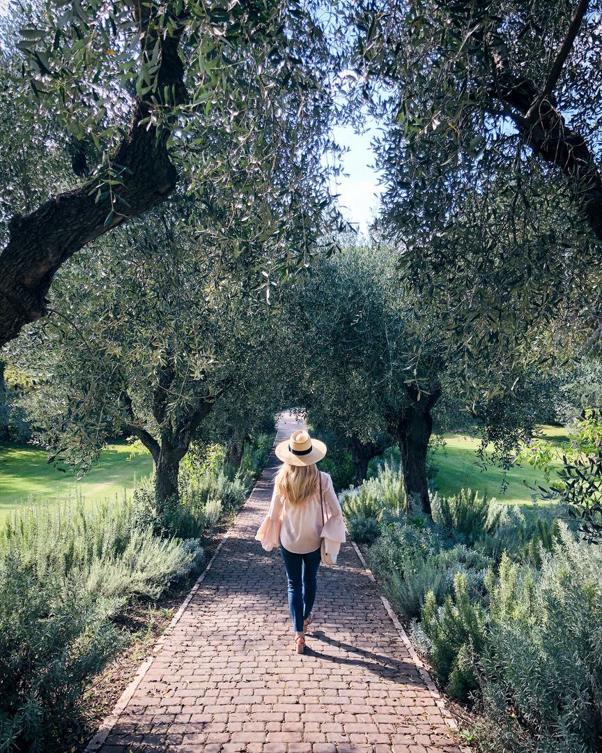 Woman Walking through Lush Garden Pathway in Autumn