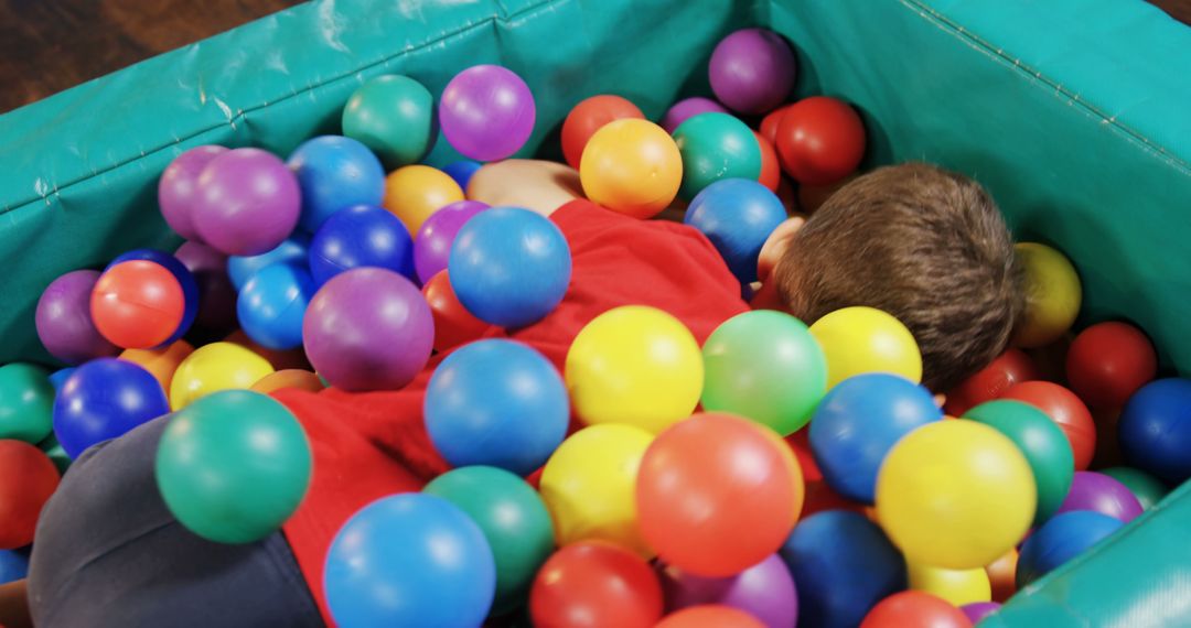 A child is immersed in a colorful ball pit, with copy space - Free Images, Stock Photos and Pictures on Pikwizard.com