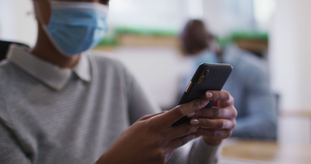 Person wearing face mask using smartphone in office - Free Images, Stock Photos and Pictures on Pikwizard.com