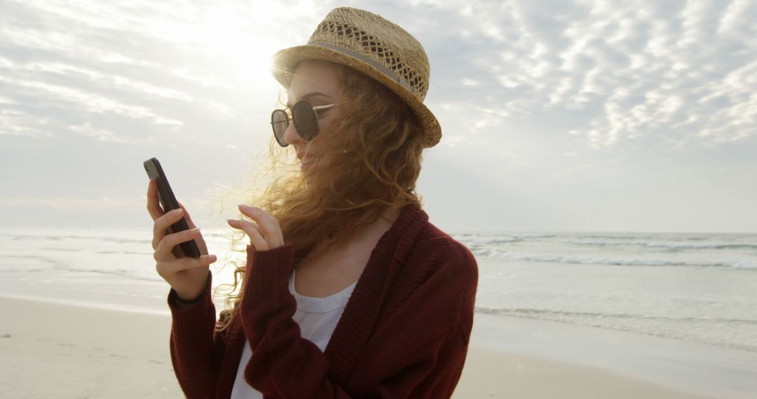 Young Woman Using Smartphone at Beach on Sunny Day - Free Images, Stock Photos and Pictures on Pikwizard.com