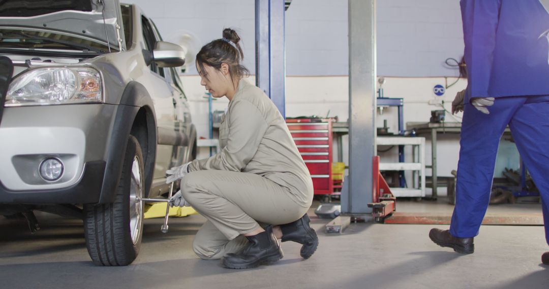 Image of caucasian female car mechanic changing tyre - Free Images, Stock Photos and Pictures on Pikwizard.com