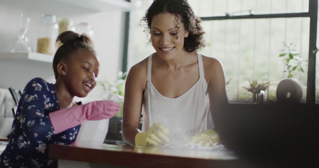 Mother and Daughter Smiling While Cleaning Together at Home