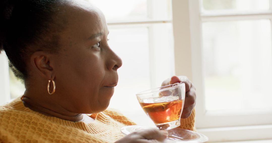 Senior Woman Enjoying Hot Beverage by Window at Home - Free Images, Stock Photos and Pictures on Pikwizard.com