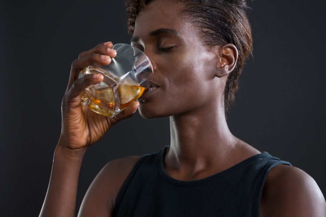 Androgynous man drinking whiskey from glass - Free Images, Stock Photos and Pictures on Pikwizard.com