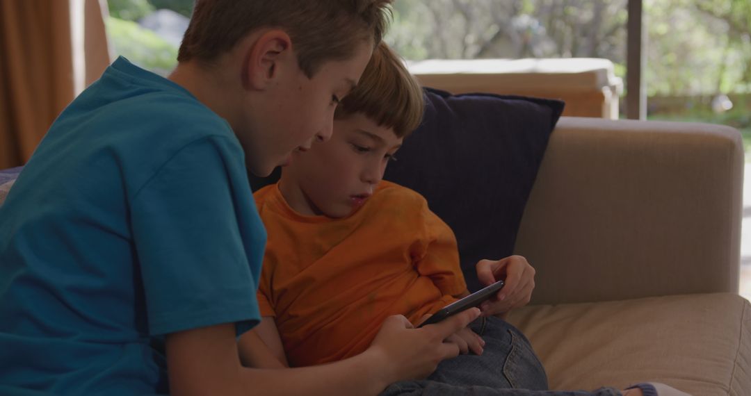 Two Boys Playing on Smartphone While Sitting on Couch at Home - Free Images, Stock Photos and Pictures on Pikwizard.com