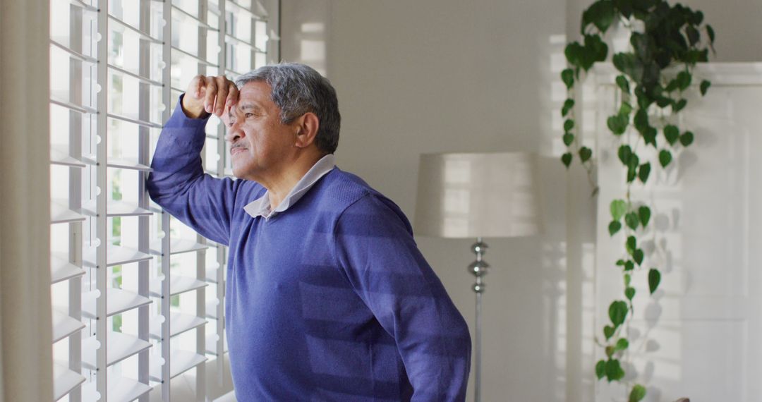 Senior Man Looking Thoughtfully through Window at Home - Free Images, Stock Photos and Pictures on Pikwizard.com