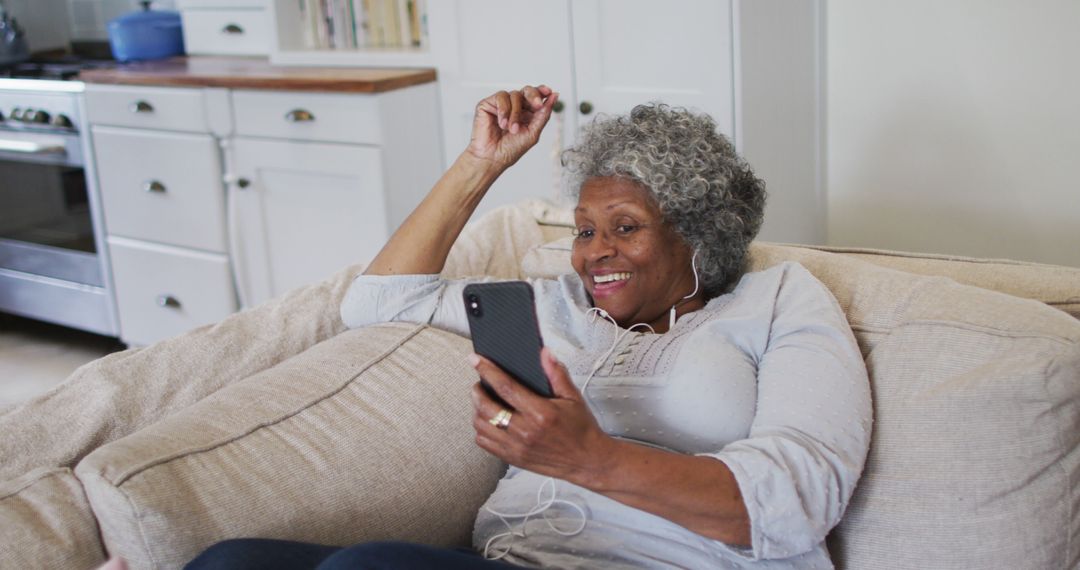 Elderly Woman Smiling While Talking on Smartphone with Earphones - Free Images, Stock Photos and Pictures on Pikwizard.com