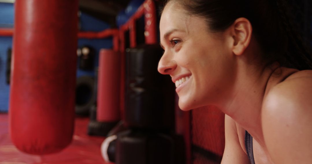 Smiling Woman In Boxing Gym Next to Punching Bags - Free Images, Stock Photos and Pictures on Pikwizard.com